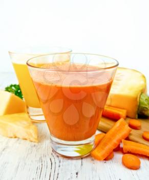 Two glassfuls juice of pumpkin and carrot, the vegetables on the background light wooden boards