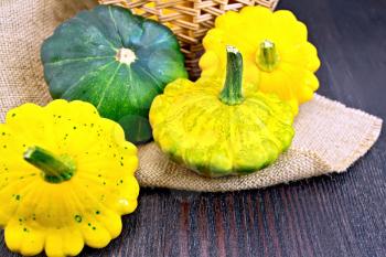 Yellow and green squash on sackcloth and wicker basket on the background of a wooden table