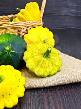 Yellow and green squash on sackcloth and wicker basket on the background of wooden boards