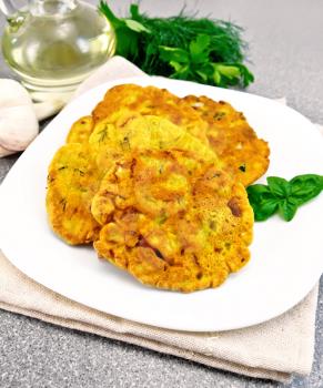 Indian chick-pea flour flatbreads with zucchini and fresh herbs, basil in a plate on a napkin, garlic and oil in a decanter, dill on the background of a granite table