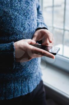 The man is using a smartphone. Modern mobile phone in hand.