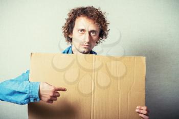 Curly man with empty cardboard. On a gray background.