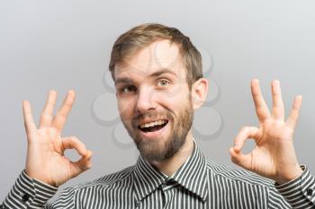man  is OK sign while standing against grey background