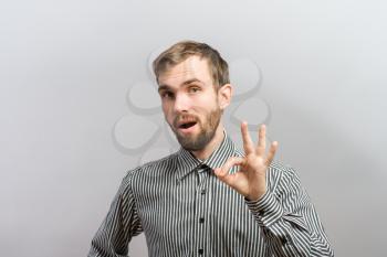 man  is OK sign while standing against grey background