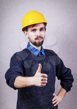 young man in a yellow hard hat showing thumb up