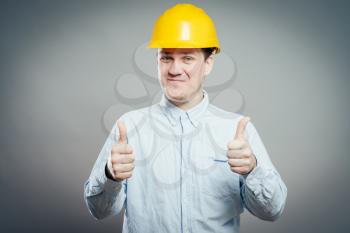 Portrait of smiling handyman with tools and paper showing thumbs up sign   isolated on  white background