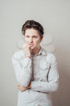 Closeup portrait of a young handsome man biting his finger nails with a craving for something or anxious. Negative human emotion facial expression feeling