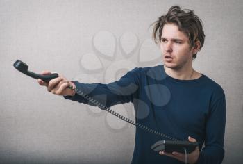 Young man with office or home phone. On a gray background.