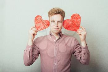A young man holding two red hearts in hands