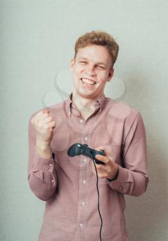 portrait of a young man plays on the joystick to the console