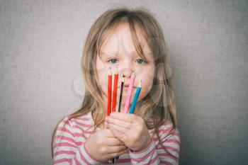 first grader holding colorful pencils 