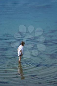 Young boy standing and looking in the clear water (vl)
