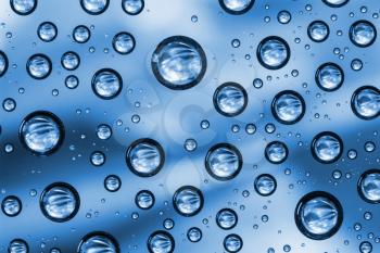 Water drops on transparent glass on blue background