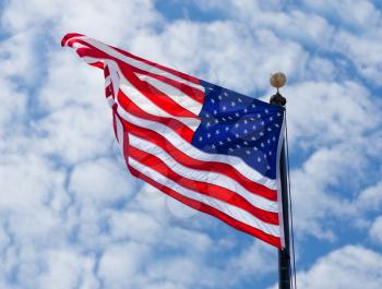 USA flag waving on the wind on cloudy sky background
