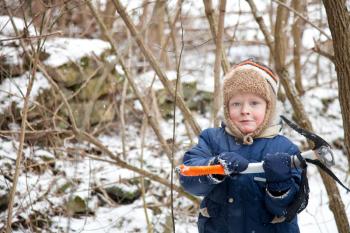 Small boy with ice axe in the forest
