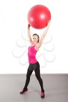 Athletic young woman with red ball on the floor
