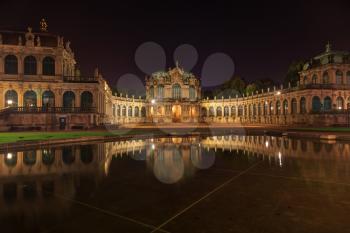 Dresden Zwinger palace panorama with illumination at night and water reflection, Germany
