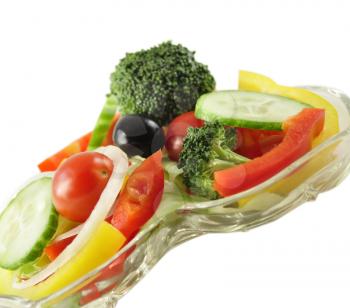 a fresh vegetable salad in a glass dish on white background