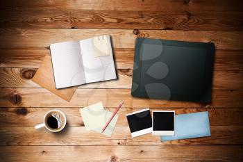 Workspace with coffee cup,  tablet pc, instant photos, note paper and notebook on old wooden table 