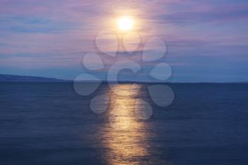 Full moon rising above mountain lake