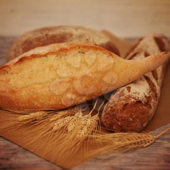 Different breads and wheat on wooden table. Food background