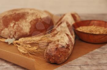 Different breads, wheat and grains on wooden table