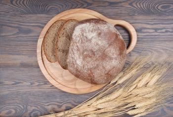 Bread and wheaten ears on wooden background top view