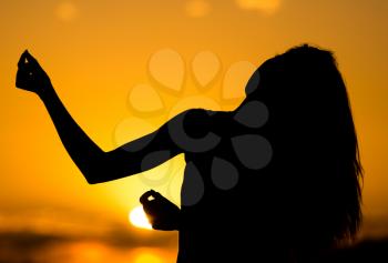 Silhouette of a girl with long hair at sunset .