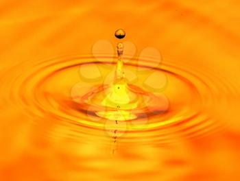 a drop of water falls in a golden water. macro