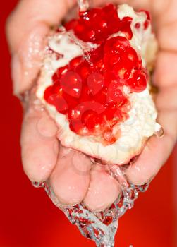 Ripe red pomegranate in her hand in water
