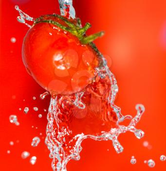 ripe tomatoes in water on a red background