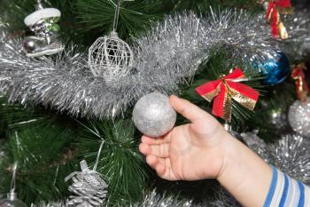 toy on the Christmas tree in a child's hand for the New Year