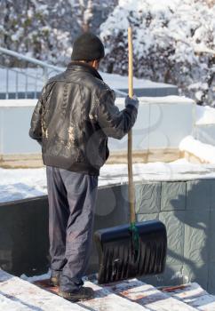 Worker cleans snow shovel in the nature