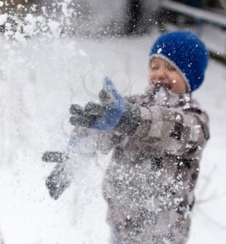 Boy playing with snow in winter