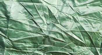 Green crumpled fabric as background . Abstract texture