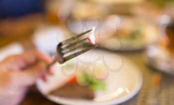 Radish on fork in hand in restaurant .