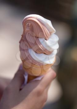 Ice cream in a waffle cup in a hand .