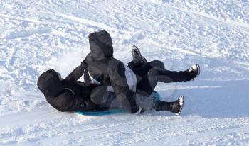 two guy riding the hills on sleds
