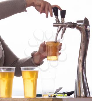 Barman pours beer into a plastic glass .