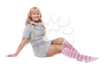 Young beautiful blonde in a striped socks sits on the floor in the studio. Isolate on white.