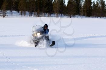 man riding a snowmobile on a background of forest