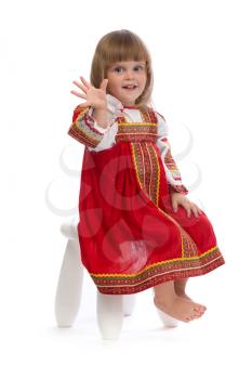 Little girl in red traditional dress on a chair. Isolate on white.