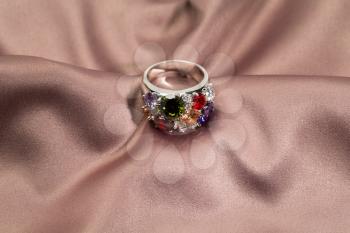 Precious ring with stones on satin brown background