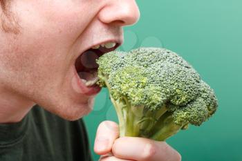 Royalty Free Photo of a Man Eating Broccoli