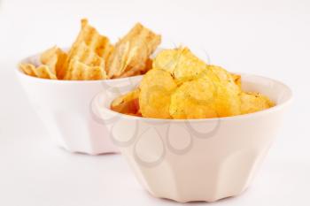 Potato and wheat chips in bowls isolated on gray background.