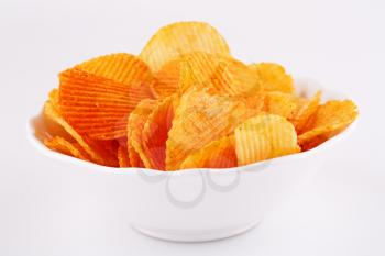 Potato chips in white bowl isolated on gray background.