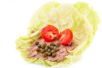 Meat pate with capers and tomato on lettuce leaves.