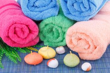 Colorful rolled towels with leaves, soaps and stones closeup picture.