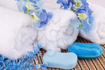 White towels with blue flowers and soaps closeup picture.
