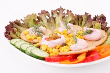 Cream, sweet corn and dill on crackers and vegetables in white plate.